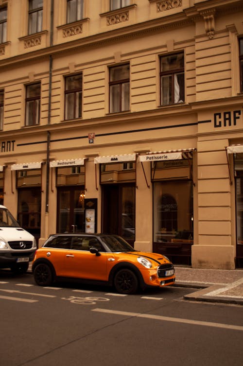 Orange Car Parked on the Street Near a Coffee Shop