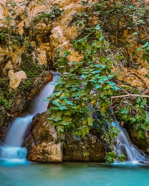 Waterfalls Between Brown and Mossy Rocks