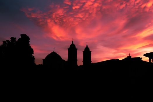 Silhouetted church towers against a vivid sunset sky, capturing the beauty of twilight.