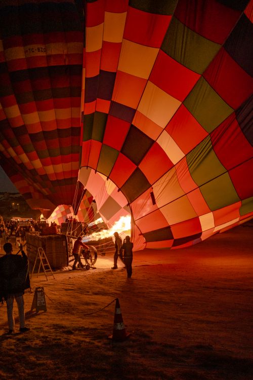 Free Vibrant hot air balloons being inflated at night with visible flame and crowd. Stock Photo