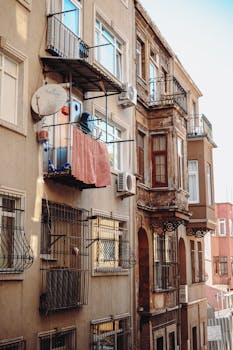 Charming apartment building exterior capturing balconies, air conditioners, and architectural details in daylight.