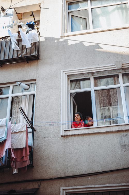 Free Urban residential building with laundry hanging outside and two people looking out of windows. Stock Photo