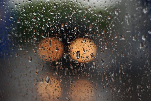 Close-up of raindrops on a window capturing blurred city lights at night, creating a moody ambiance.