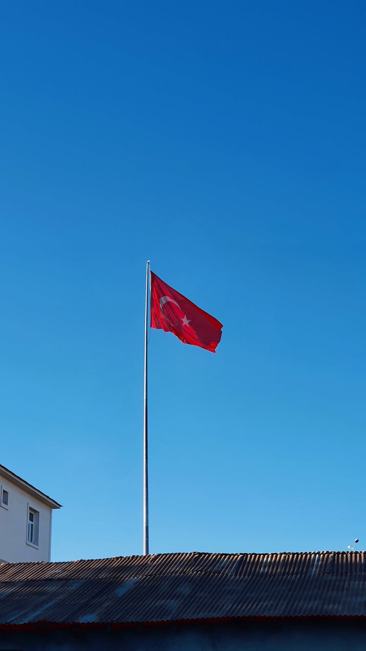 Flag On Building Roof On Blue Sky Background