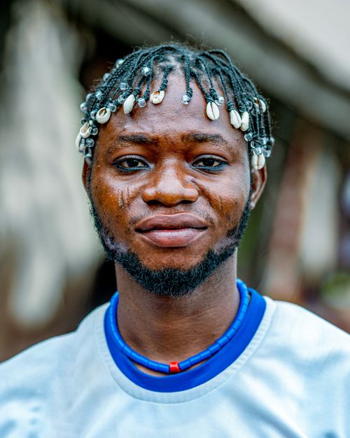 Free Captivating portrait of a man wearing a white shirt with a beaded hairstyle featuring shells. Stock Photo