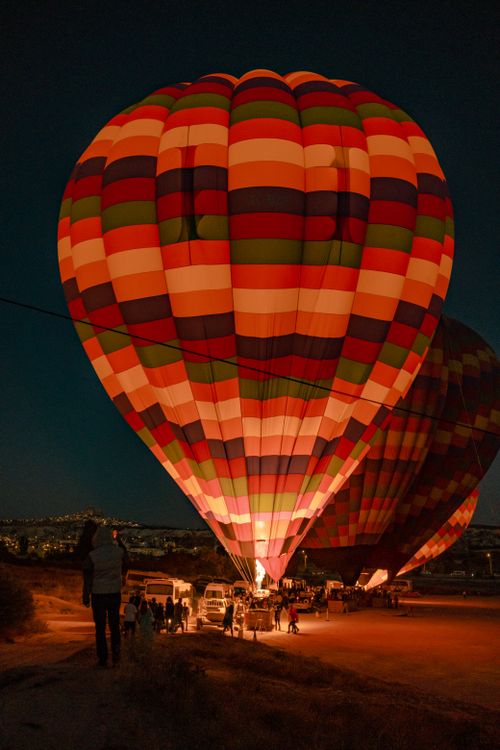 Free Vibrantly colored hot air balloons light up the night sky in an open field, creating a magical evening scene. Stock Photo