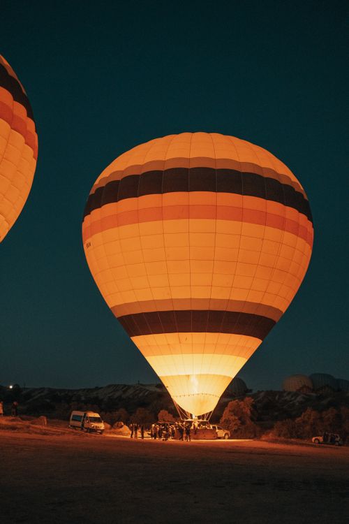 Free A glowing hot air balloon lit up at night in an open field, surrounded by vehicles and people. Stock Photo