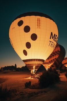 Glowing hot air balloons at night, creating a serene scene in an open field under a clear sky.