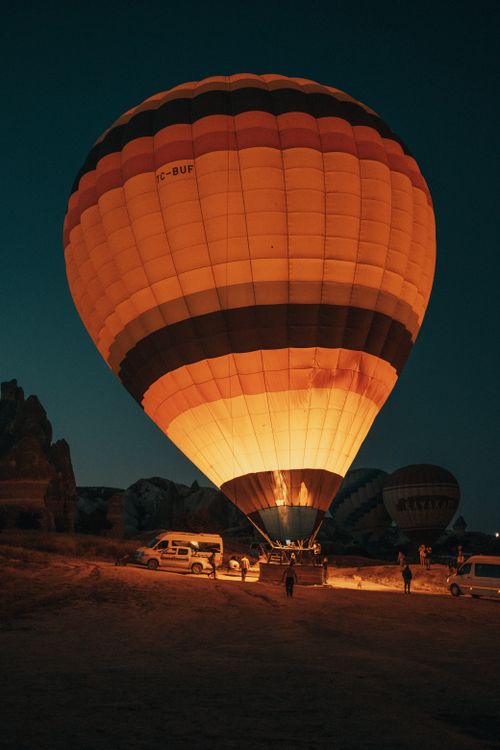 Free A hot air balloon glowing warmly against the night sky, ready for takeoff. Stock Photo
