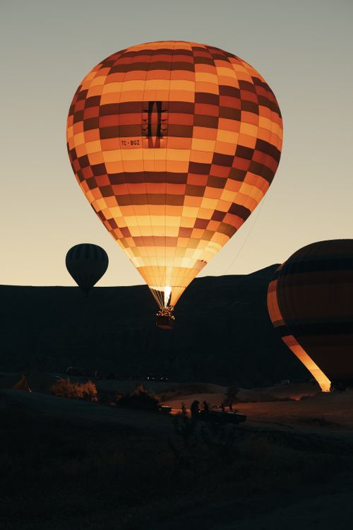 Free Glowing hot air balloons rise over a picturesque valley at dawn, a breathtaking travel adventure. Stock Photo