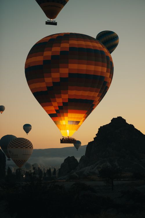 Free Hot air balloons rising at sunrise over scenic mountains, creating a serene and colorful landscape. Stock Photo