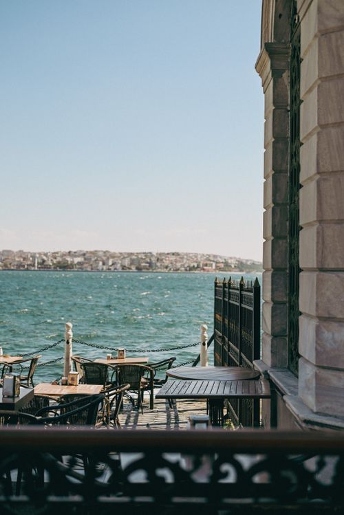 Free Outdoor dining area by the sea with cityscape in the background. Stock Photo