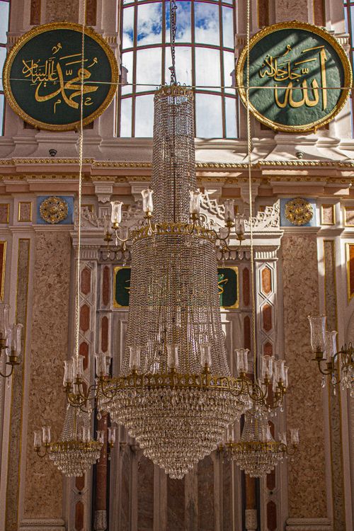 Free Luxurious crystal chandelier in an ornate interior with Islamic calligraphy details. Stock Photo