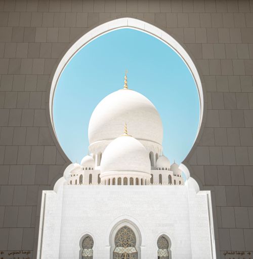 Free Stunning view of the Grand Mosque dome framed by an arch, under a bright blue sky. Stock Photo