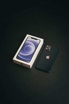 Minimalist shot of iPhone 12 Mini and box on a dark surface.