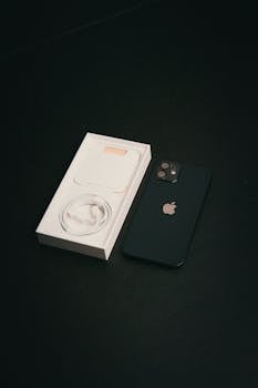 A smartphone with its charger box on a black surface, showcasing modern technology.