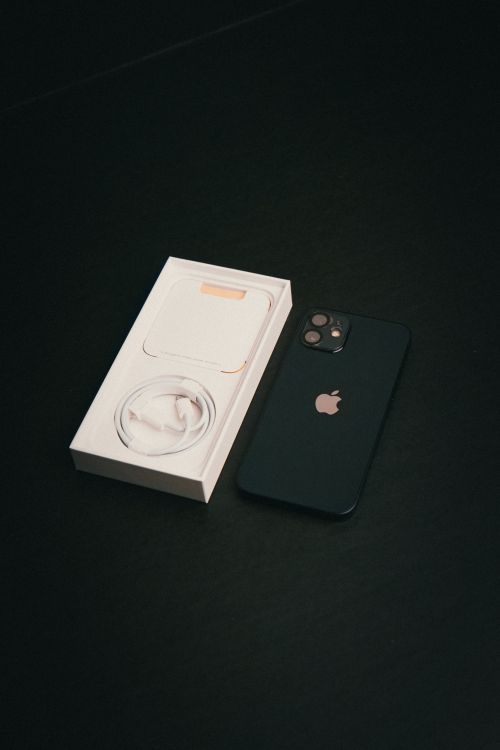 Free A smartphone with its charger box on a black surface, showcasing modern technology. Stock Photo