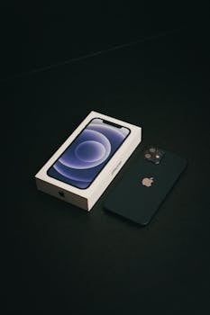 Smartphone and box on a dark surface, showcasing technology design.