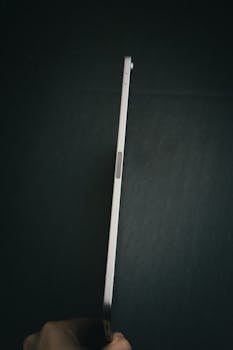 Sleek smartphone held sideways against a dark background, showcasing minimal design.