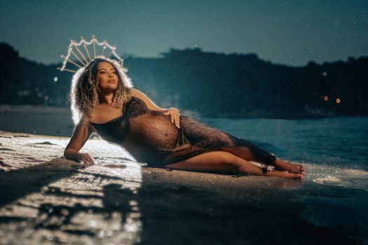 Pregnant Woman Wearing a Headpiece Lying on her Side on a Beach at Night