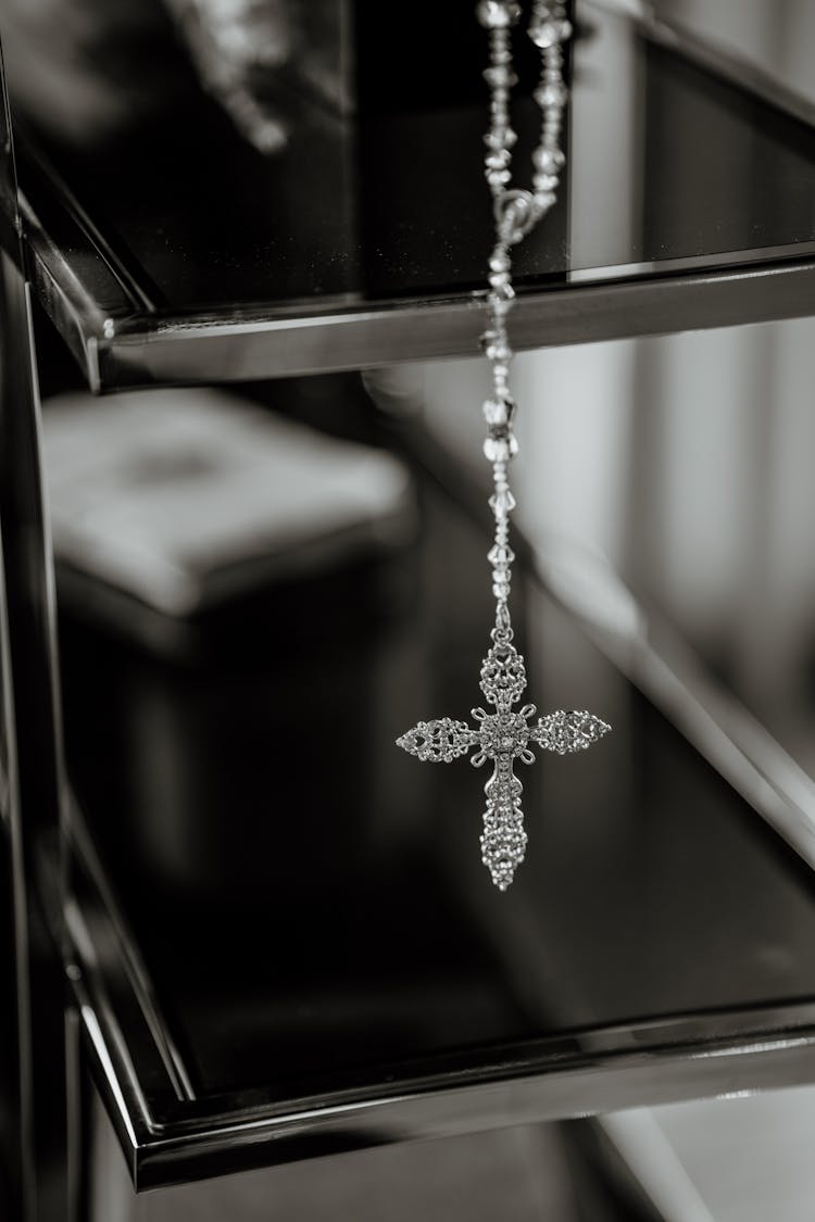 Grayscale Photo Of A Rosary Hanging On Shelves