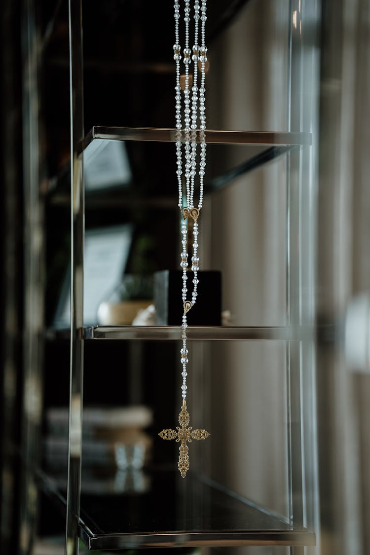 A Rosary With White Beads Hanging On Shelves