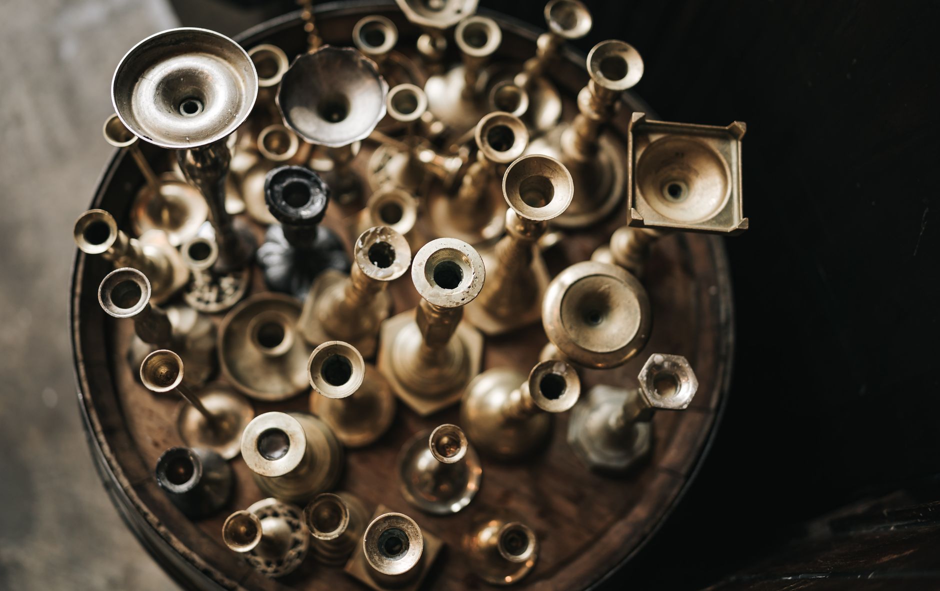 A collection of vintage brass candlesticks viewed from above, showcasing a variety of designs and forms.