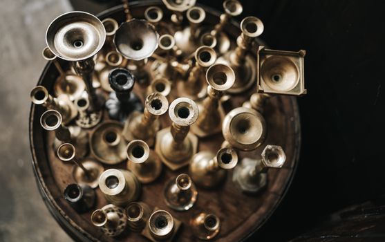A collection of vintage brass candlesticks viewed from above, showcasing a variety of designs and forms.