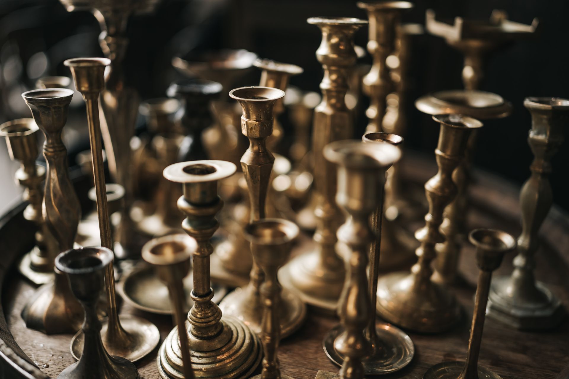 A close-up view of a collection of vintage brass and copper candle holders, showcasing metallic elegance.