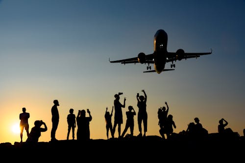 Silhouettes of People Photographing a Plane at Sunset