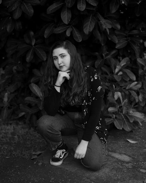 Woman in Sweatshirt Squatting Beside a Plant