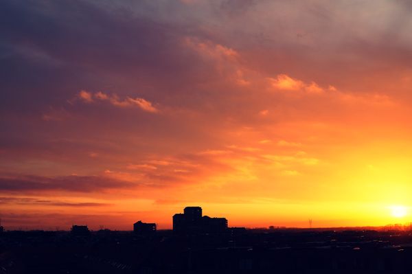 Captura de um pôr do sol deslumbrante com céus vibrantes e silhuetas de cidade, perfeito para temas de paisagens urbanas.