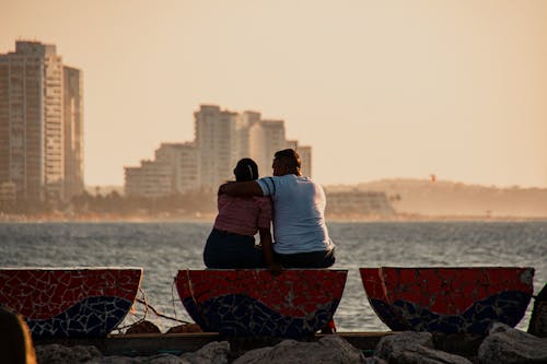 Couple Sitting on Concrete Bench Looking at the Sea