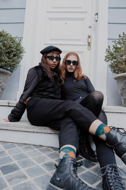 Fashionable women in black clothing and sunglasses sitting outside a doorway in Buenos Aires.