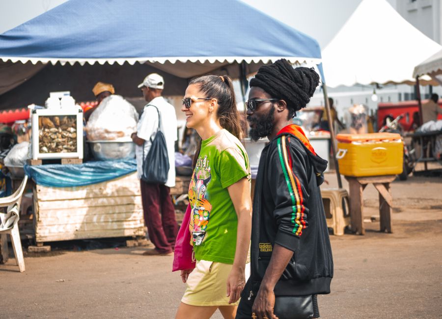 A cheerful couple enjoys a walk through a bustling market in Accra, Ghana, capturing local life and culture.