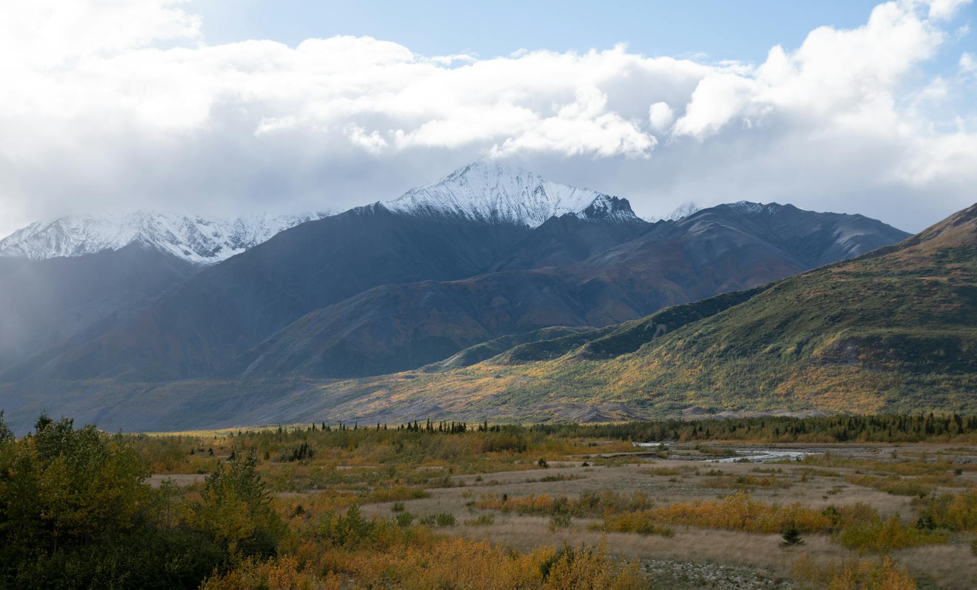 Majestic Alaskan mountains with snow-capped peaks under dramatic clouds.