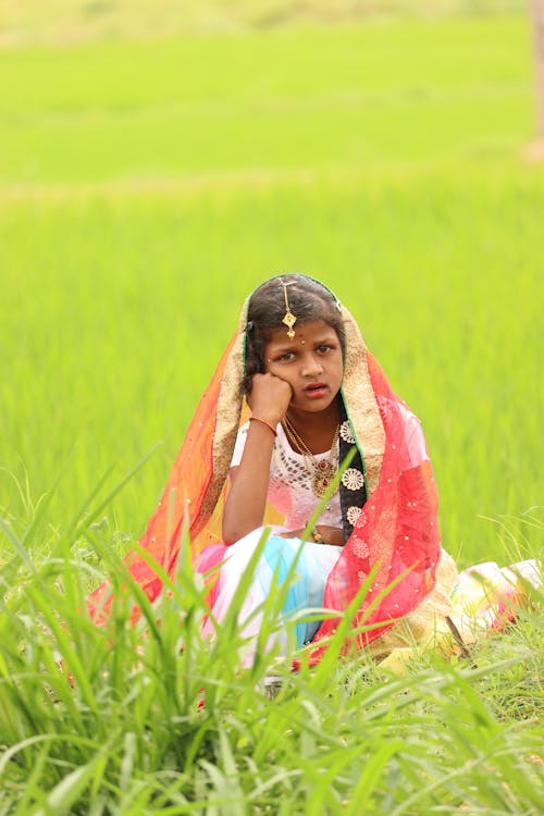 A Girl Sitting on Grass Field