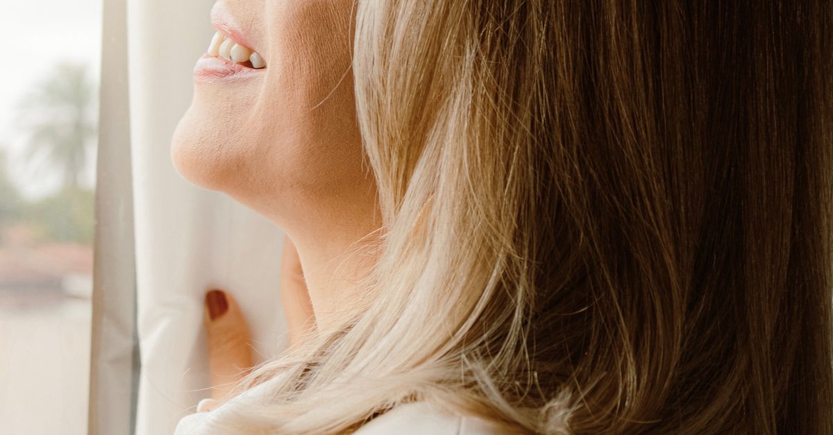 Mulher madura sorrindo em ambiente iluminado, representando saúde preventiva