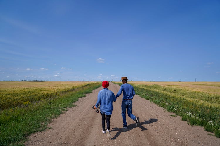 Woman And Man Running On Dirt Road Through Field