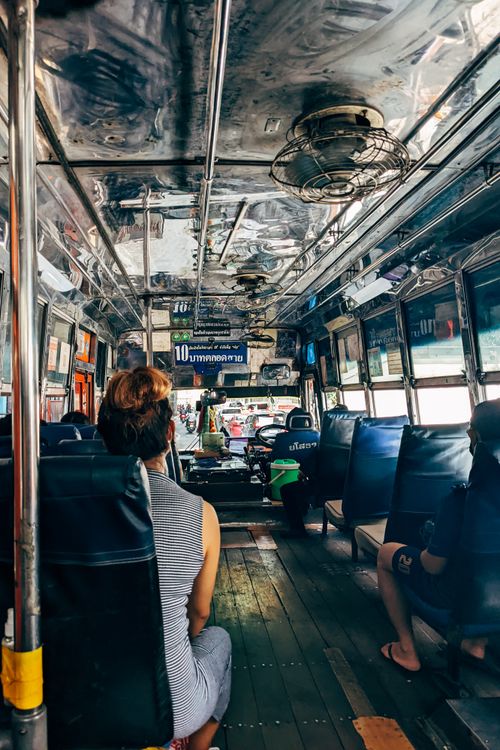 Free Passengers sit inside a vintage city bus with reflective metal ceiling, capturing a daily commute. Stock Photo