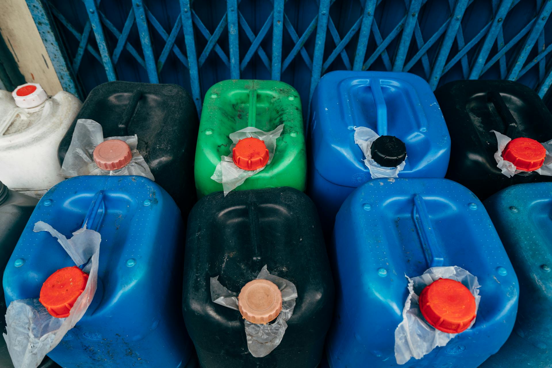 Top view of assorted colored plastic canisters used for industrial storage, featuring red caps.