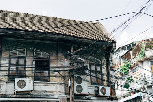 Free A weathered building with roof tiles and electric wires in an urban area, showcasing vintage architecture. Stock Photo
