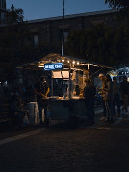 Street food stall lit at night in San Pedro Tlaquepaque, Mexico, with people gathered around.