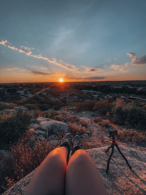 Person Sitting on Rock during Sunset