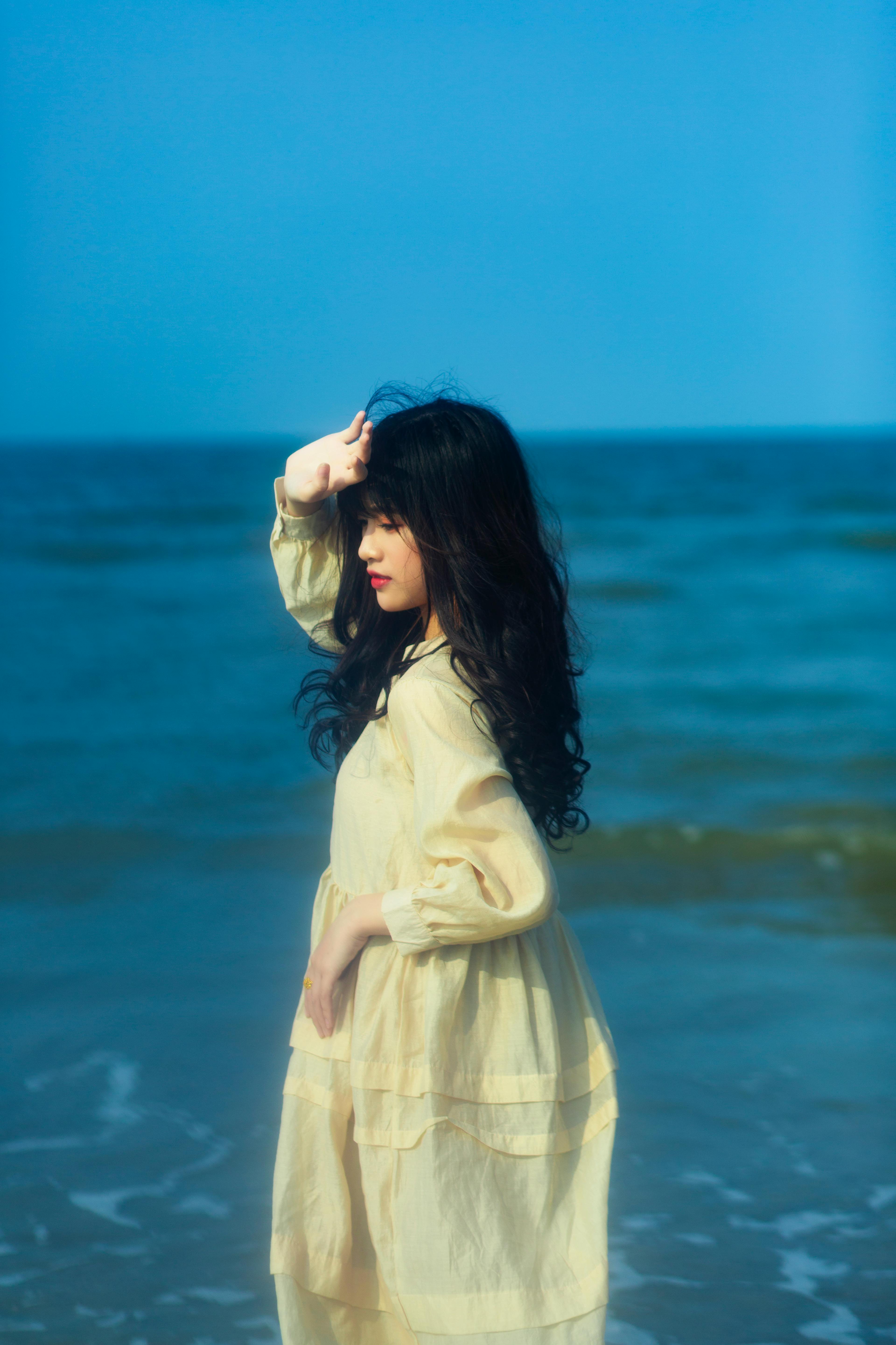 一位穿着黄色连衣裙的年轻女子在海边享受着宁静的夏日