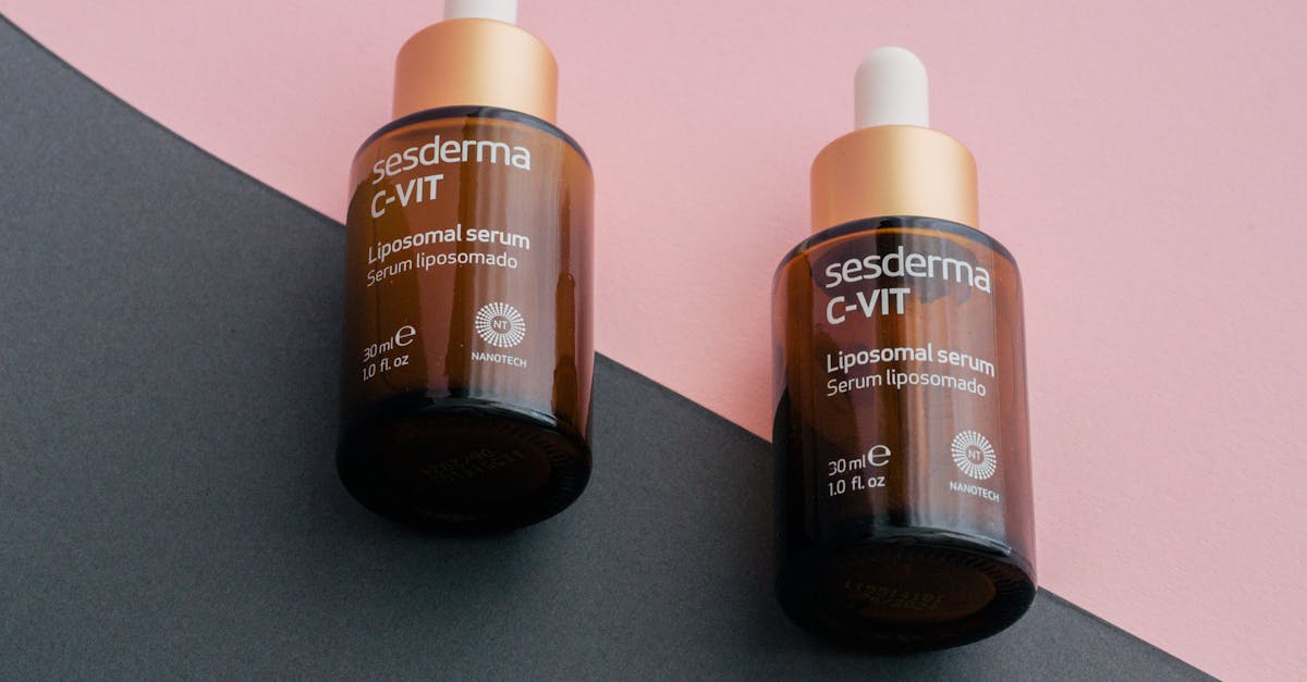 Two dropper bottles of Sesderma C-Vit liposomal serum on a pink and gray background.