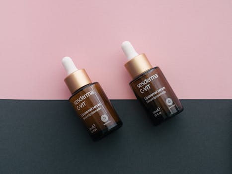 Close-up of two skincare serum bottles on a pink and black background, perfect for product photography.
