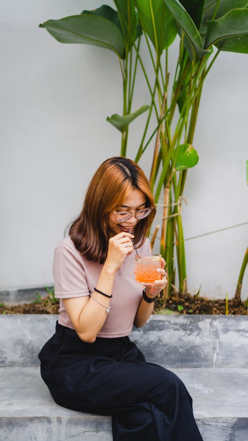 Woman in a Pink Top Drinking a Glass of Juice