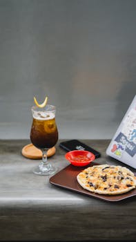 Delicious iced coffee served with a fresh pizza slice on a wooden table.