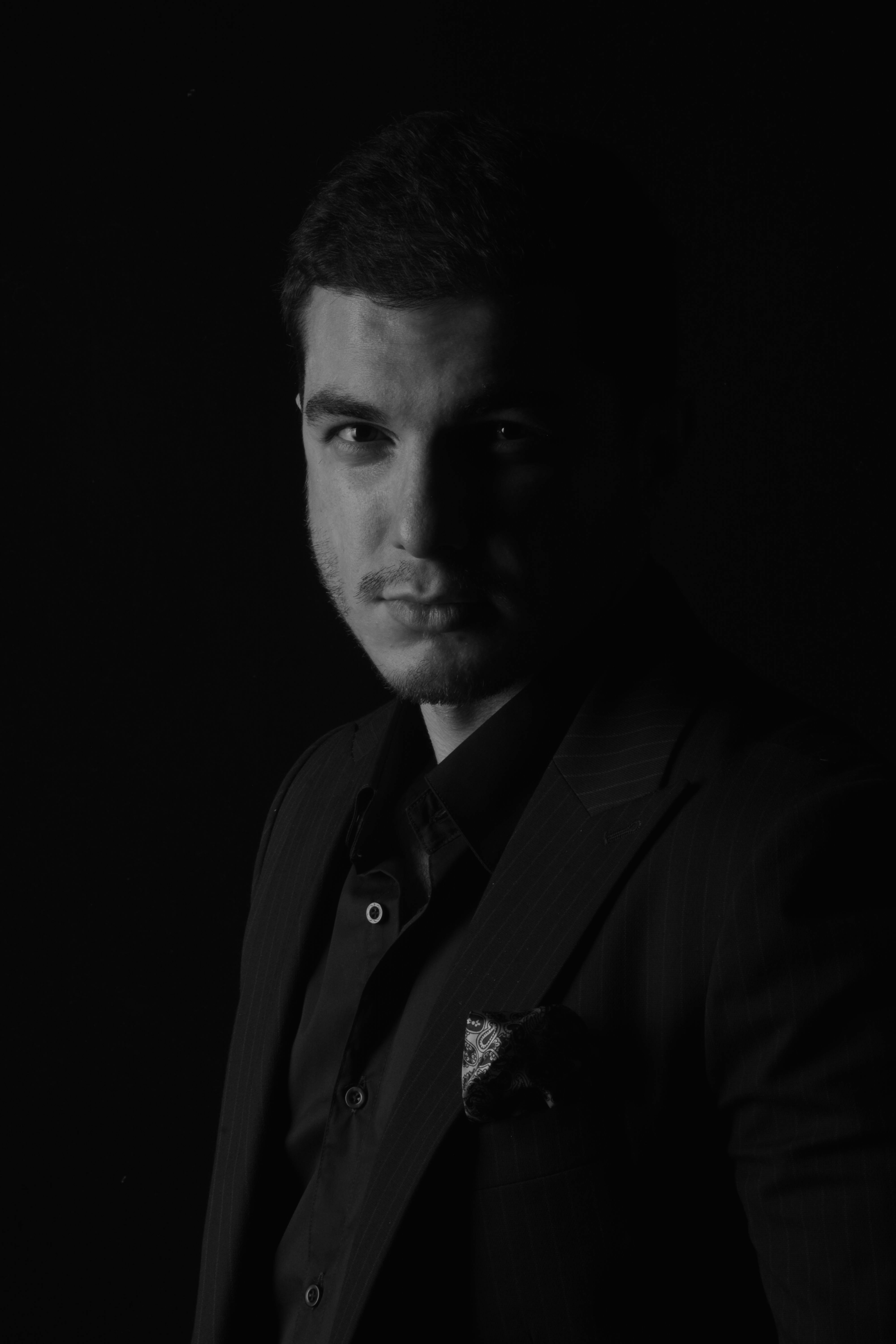 Moody black and white portrait of a man in a suit with dramatic lighting.